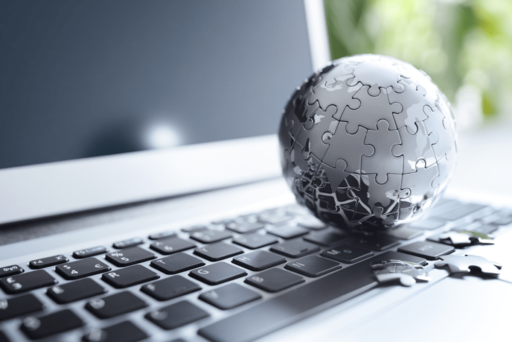 Global strategy solution concept: a close-up image of a chrome Earth jigsaw puzzle on an open laptop keyboard